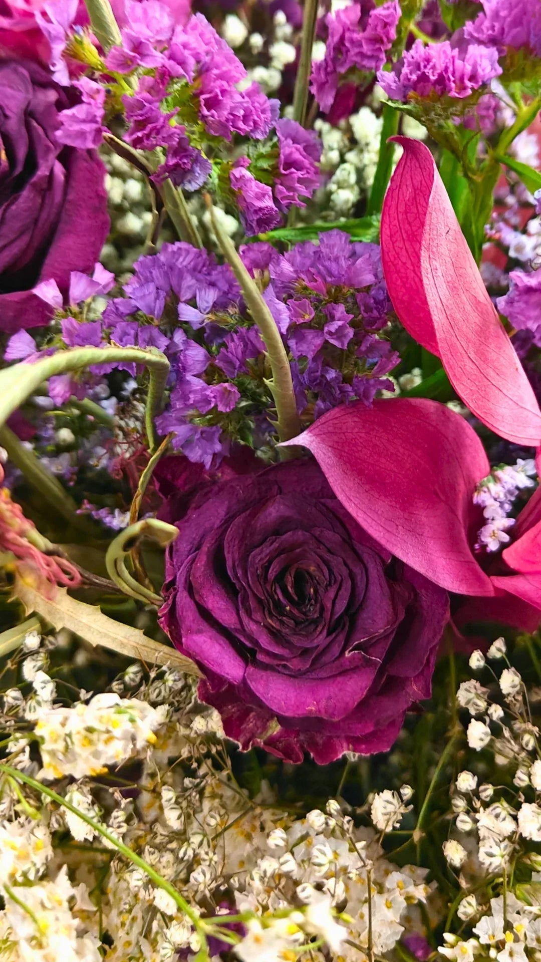 זר פרחים מגווונים עם ורדים סגולים פרחים קטנים לבנים ועלים ורודים, צילום מקרוב