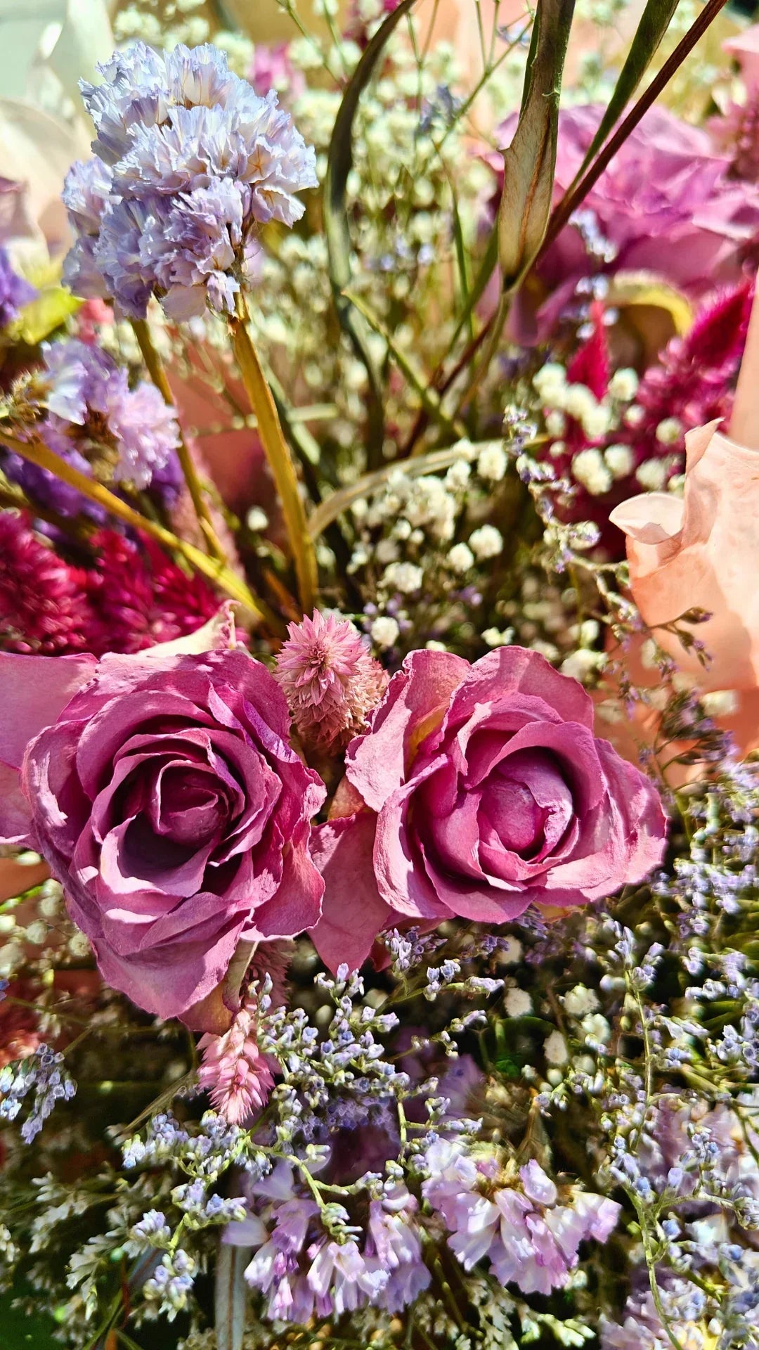 זר פרחים יבש עם ורדים סגולים ופרחים קטנים לבנים וסגולים לרקע טבעי ועיצוב עדין